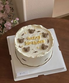 a birthday cake with white frosting and brown teddy bears on it sitting on top of a table