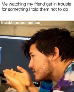 a man sitting in front of a computer screen with his hands clasped to the keyboard