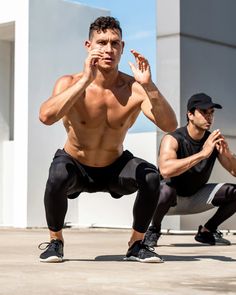 two men are doing yoga outside in front of a building and one man is holding his hand up to his face