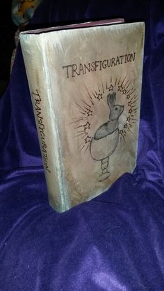 an old book with the words transfiguration on it sitting on a purple blanket