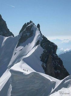 three people hiking up the side of a snow covered mountain