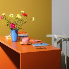 flowers in a blue vase on an orange table