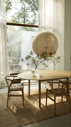 a table with two chairs and a vase on it in front of a large window