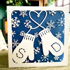 a card with mittens and snowflakes in the shape of a heart on it