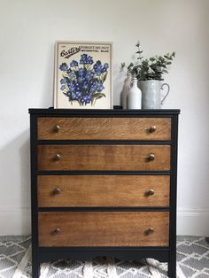 an old dresser with blue flowers on top and a vase in the corner next to it