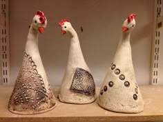 three ceramic chickens sitting on top of a shelf