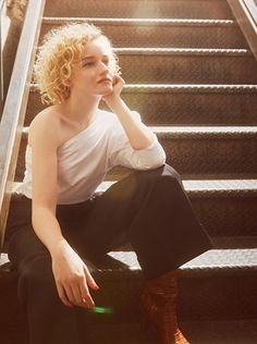 a woman sitting on the stairs with her hand under her chin