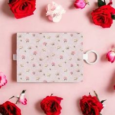 red roses and white coffee mugs on pink background with floral wallpaper in the corner