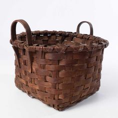 a brown woven basket with handles on a white background