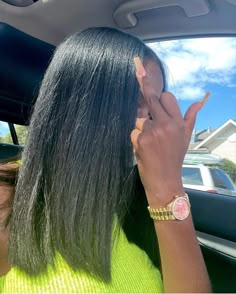 a woman with long black hair sitting in a car talking on her cell phone