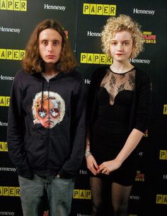 two people standing next to each other in front of a wall with the words paper on it