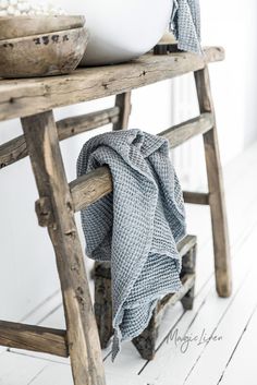 a wooden bench with a bowl on top of it and a towel draped over the seat