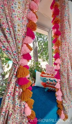 a canopy bed covered in pink and orange tassels