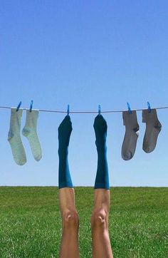 someone hanging out their socks on a clothes line in the middle of a grassy field