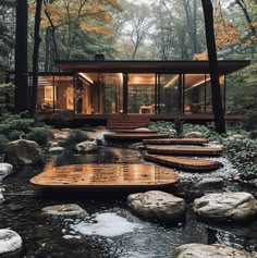 a house in the woods surrounded by rocks and water with steps leading up to it