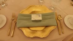 a place setting with silverware and napkins on a gold plated table cloth