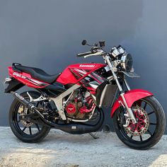 a red motorcycle parked next to a gray wall