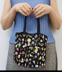 a woman is holding a black purse with many pins and magnets on the front