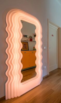 a large mirror sitting on top of a wooden floor next to a white wall and door