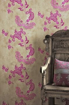 a wooden chair sitting next to a wall covered in pink and white paisley print fabric