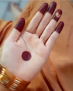 a woman's hand with red nail polish and gold bracelets on her wrist