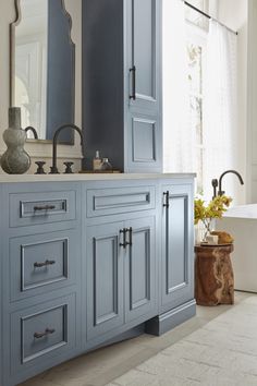 a bathroom with blue cabinets and a large mirror