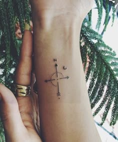 a woman's arm with a small compass tattoo on it