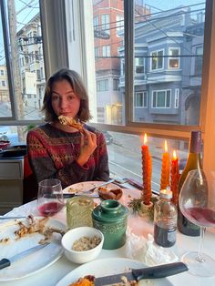 a woman sitting at a table with food in front of her and candles on the table