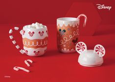 two mugs with candy canes in front of them