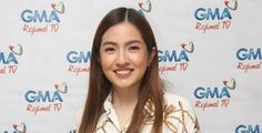 a woman standing in front of a red carpet with the words gma regional tv on it