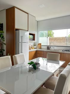 a white table and chairs in a room with wooden cabinets, windows, and a refrigerator