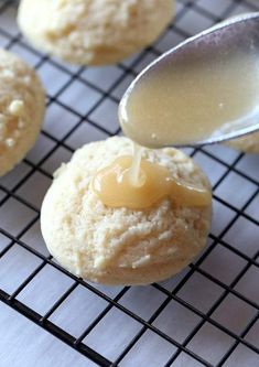 a spoon drizzling peanut butter onto cookies on a cooling rack