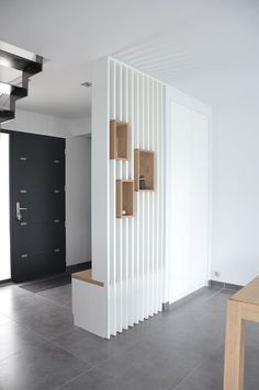 an empty room with a black door and some white panels on the wall next to a wooden table