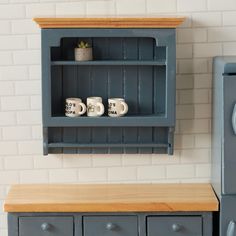 a shelf with two mugs on it next to a blue refrigerator freezer in a kitchen