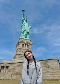 a girl standing in front of the statue of liberty