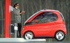 a woman standing next to a small red car