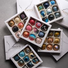 four boxes filled with assorted colored chocolates on top of a marble countertop