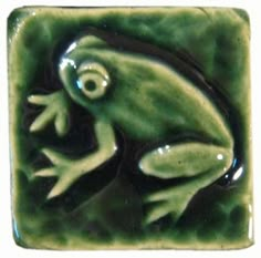 a green frog sitting on top of a tile