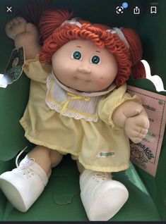 a doll with red hair sitting in a green box