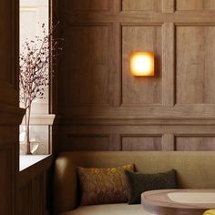 a living room with wood paneling and a round table in front of the couch