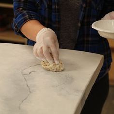 a woman in gloves is cleaning a counter top with a scrubber and dish cloth