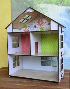 a doll house with a waterfall in the background and flowers on the wall next to it