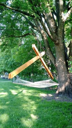 a hammock hanging from a tree next to a wooden structure in the grass