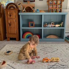 a toddler playing with toys on the floor in front of a bookshelf