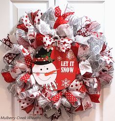 a red and silver christmas wreath with a snowman on it's front door