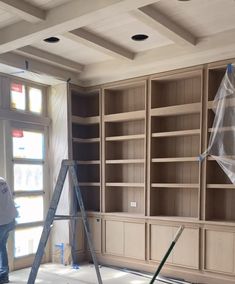 a man standing on a ladder in front of a book shelf filled with wooden shelves