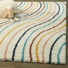 a white rug with multicolored lines on it and a stuffed animal in the middle