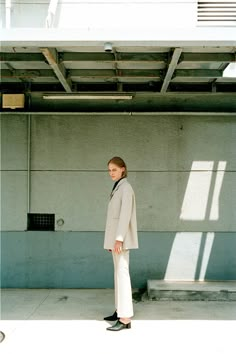 a man standing in front of a building with his back to the camera, wearing a white suit and black shoes