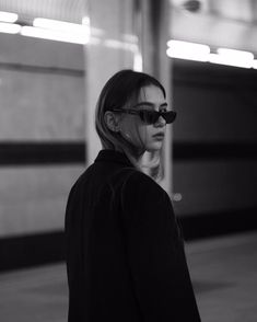 a woman in sunglasses is standing on the sidewalk