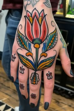 a woman's hand with tattoos on it and flowers painted on the inside of her palm